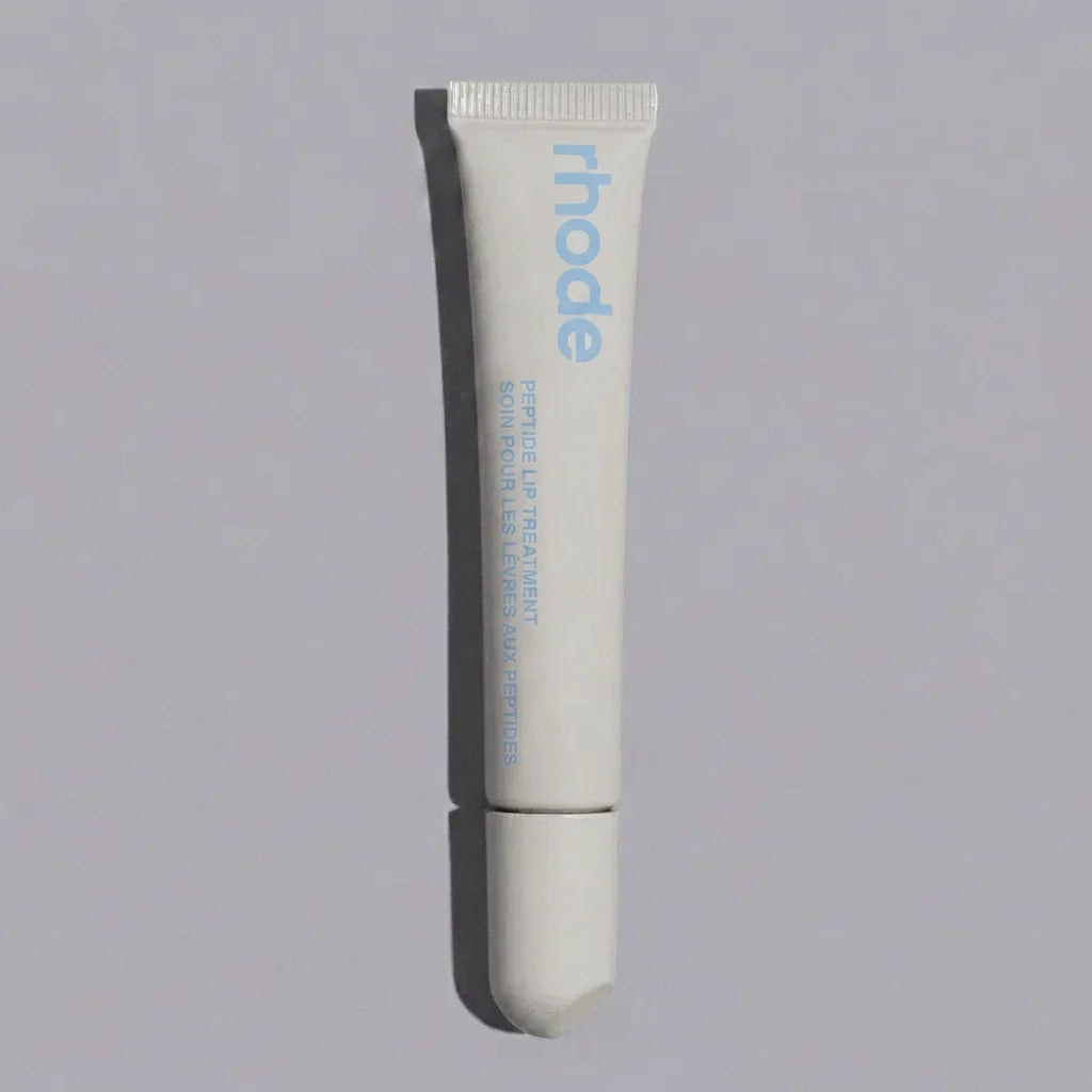 Tube of 'rhode' lip treatment on a gray background