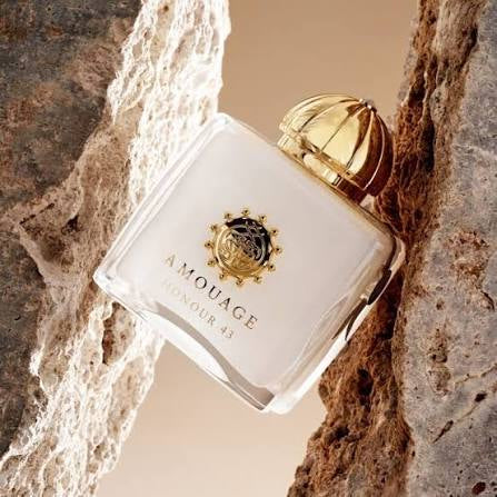 Amouage perfume bottle with gold cap on a textured stone background