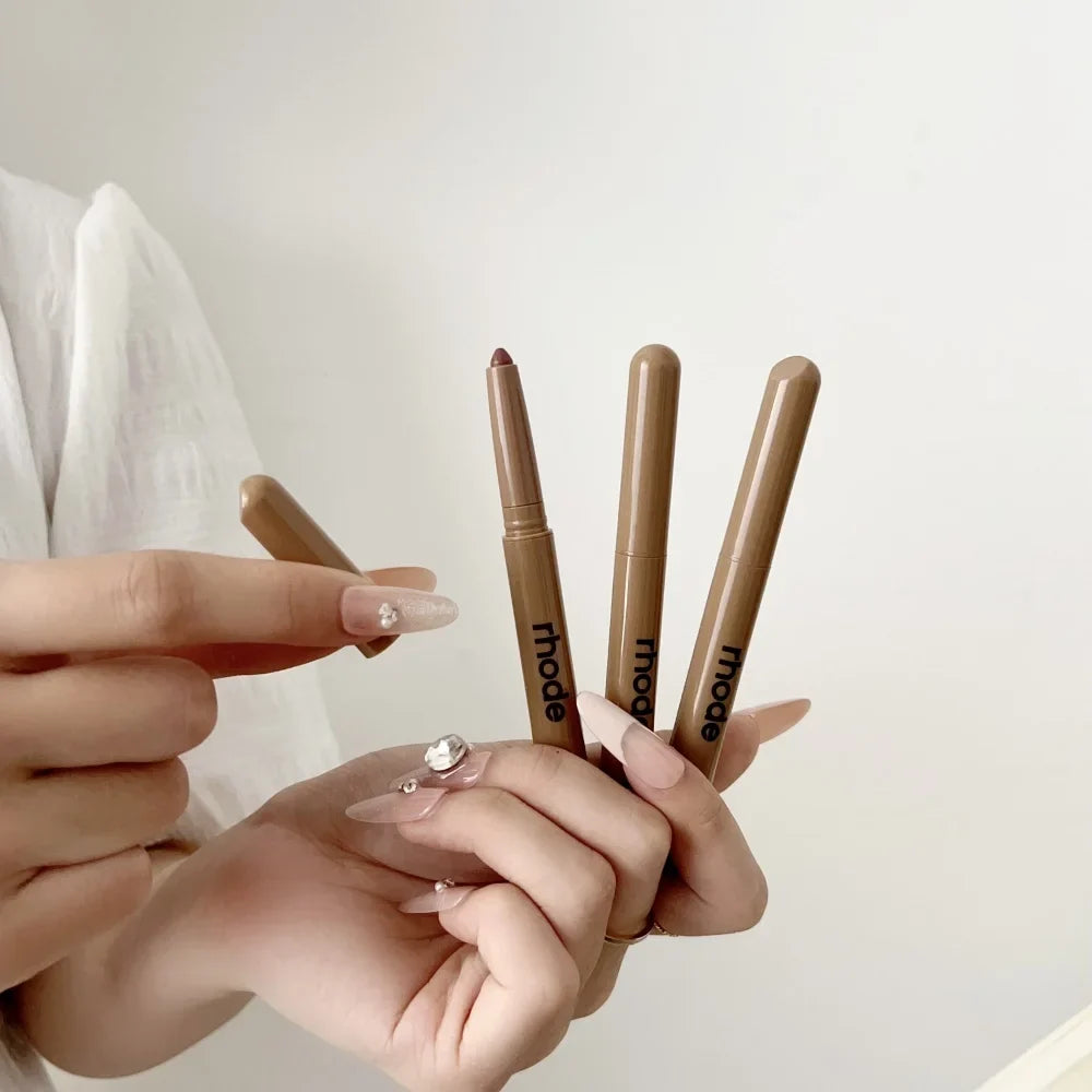 Hands holding four makeup pencils with 'itcos' branding against a neutral background