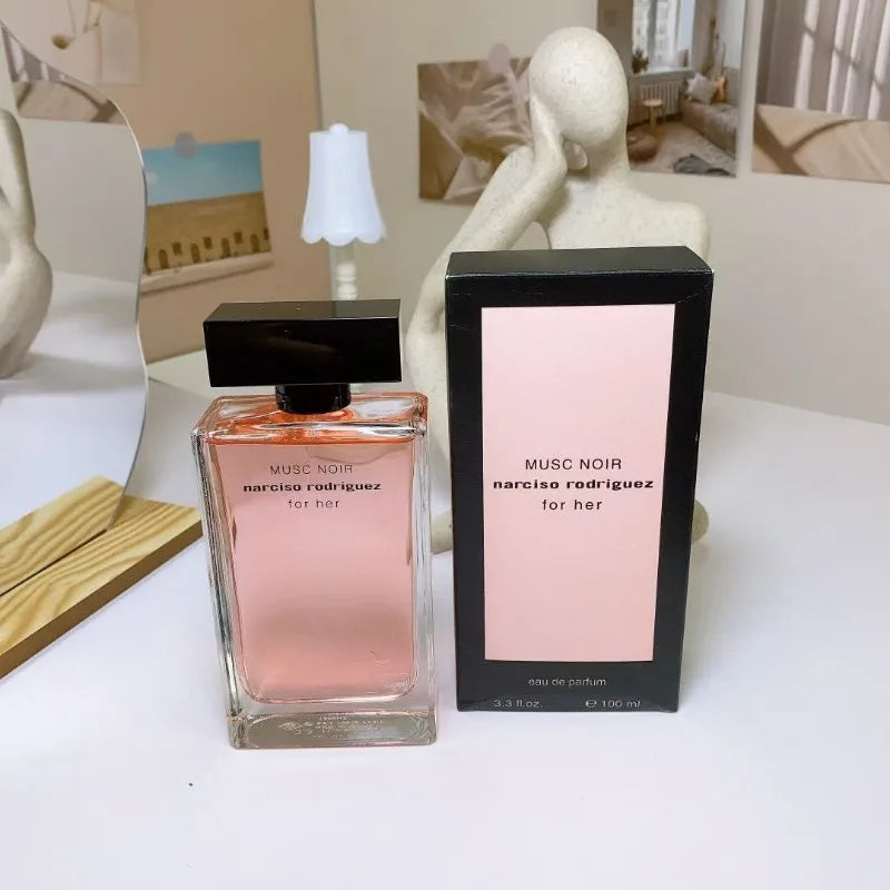 Musc Noir Narciso Rodriguez perfume bottle and packaging on a white surface with decorative elements.
