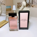 Musc Noir Narciso Rodriguez perfume bottle and packaging on a white surface with decorative elements.