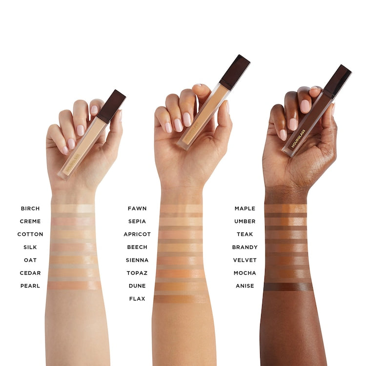 Three hands holding makeup products with color swatches on arms against a white background