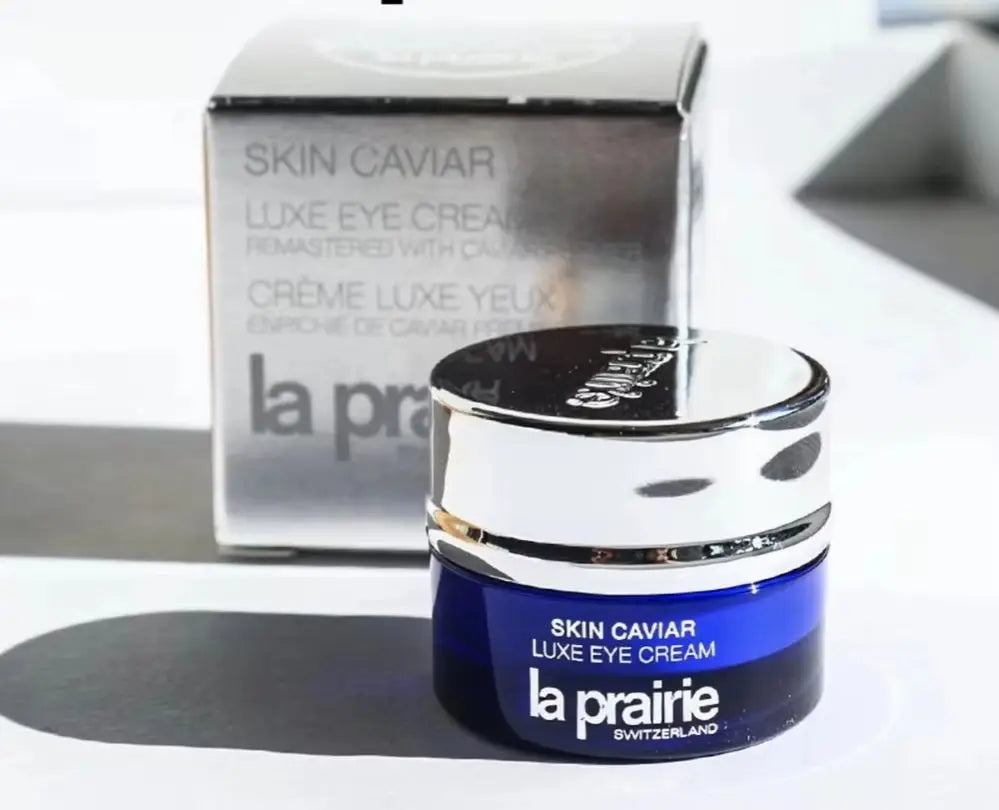 La Prairie Skin Caviar Luxe Eye Cream jar in front of its silver packaging box, on a white surface with a soft shadow.