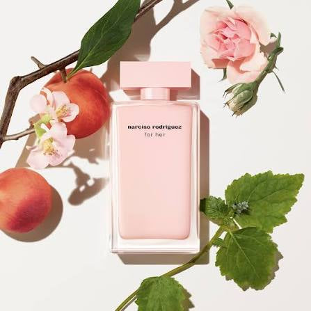 Pink Narciso Rodriguez perfume bottle with peaches and flowers on a light background