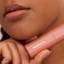 Close-up of a person wearing a pink lip color with 'Rare Beauty' lipstick visible.