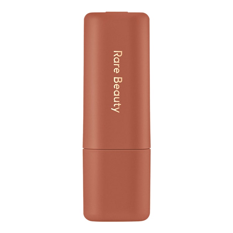 Rare Beauty lipstick in a matte terracotta color with gold vertical branding on a clean white background.