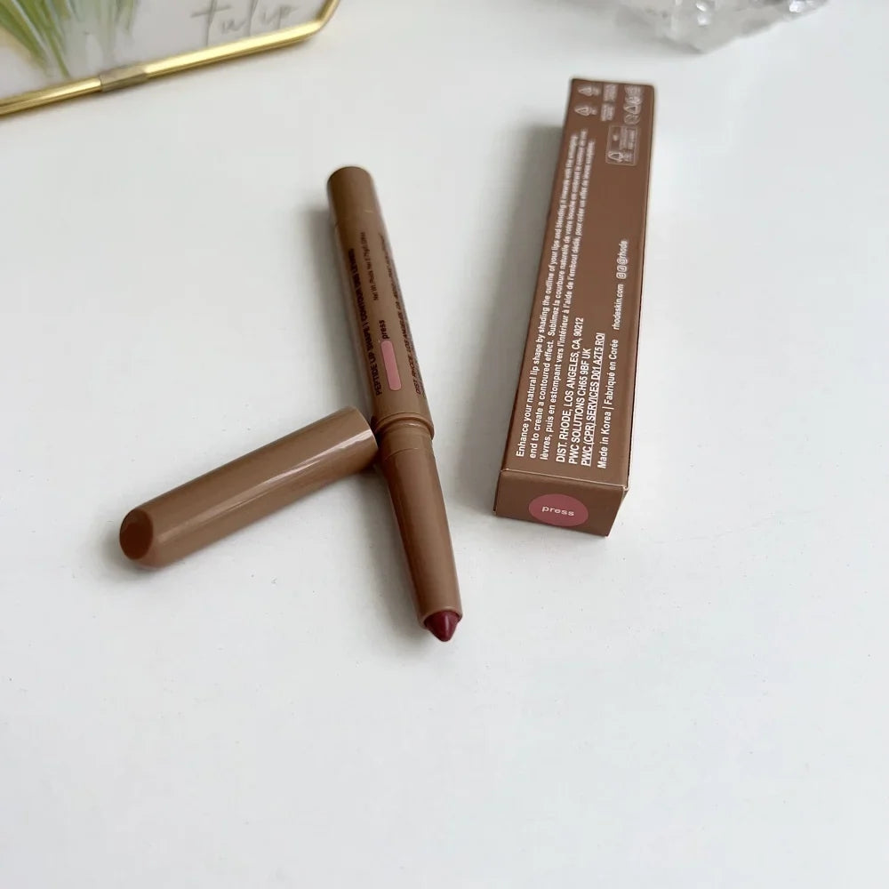 Brown lip liner with applicator and packaging on a white surface