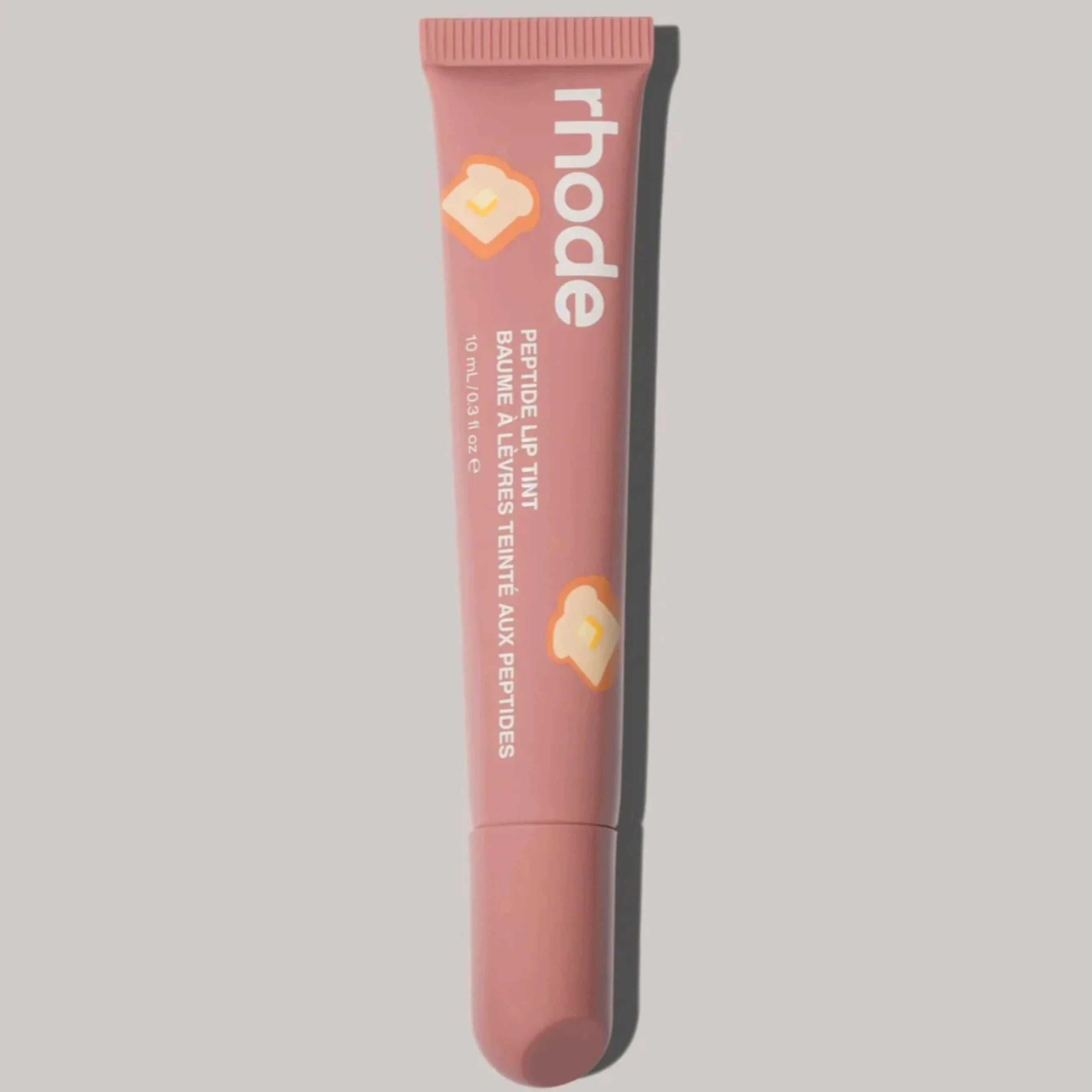Pink lip balm tube with 'rhode' branding on a gray background