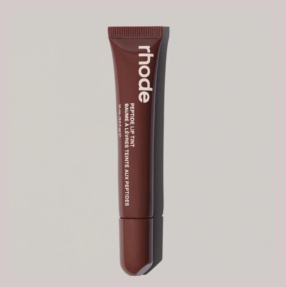 Brown lip balm tube with 'rhode' branding on a light gray background