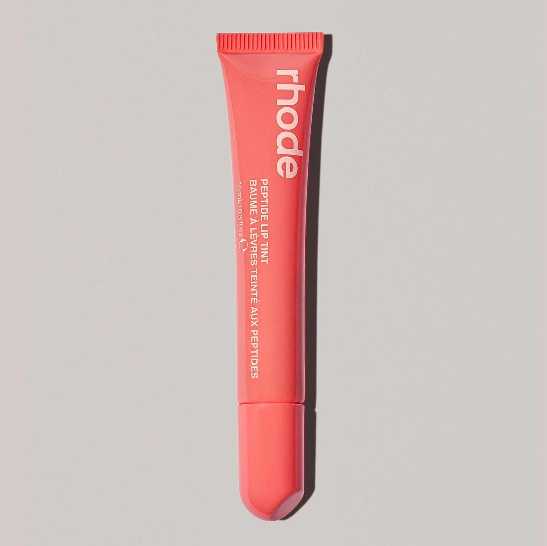 Pink lip balm tube with 'rhode' branding on a gray background