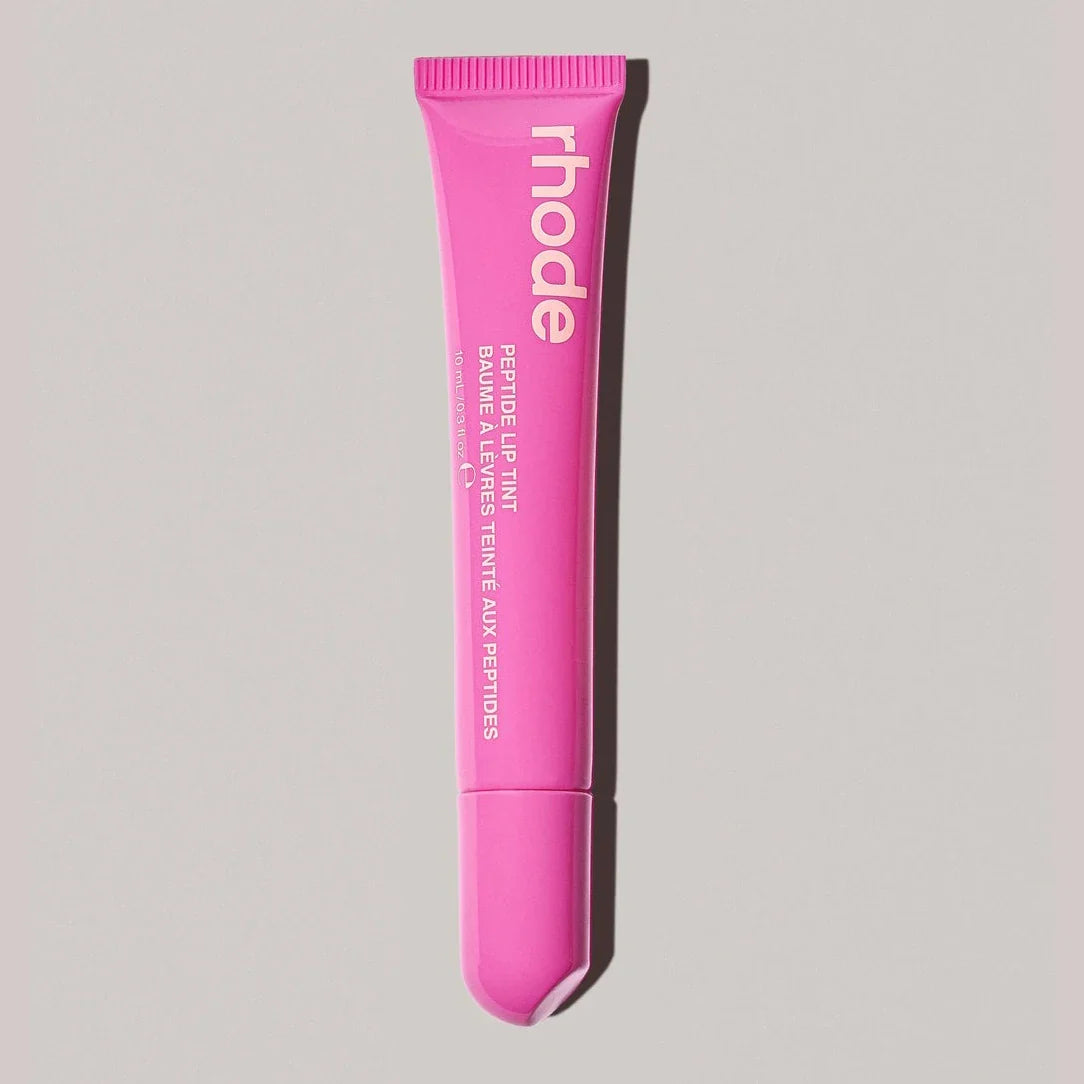 Pink lip treatment tube with 'rhode' branding on a gray background
