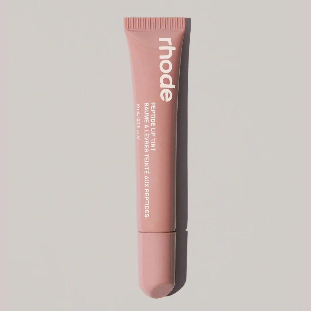 Pink lip balm tube with 'rhode' branding on a light gray background