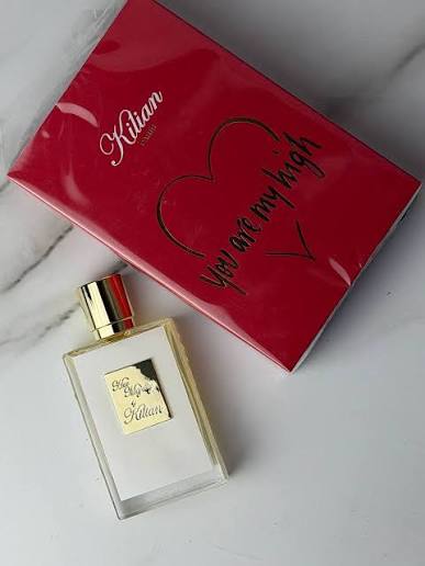 A bottle of Kilian 'You Are My High' perfume next to its red packaging box on a light marble surface.